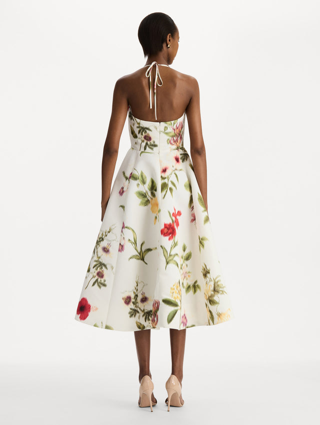 The model is wearing the Chiné Dominican Mixed-Floral Faille Cocktail Dress. Featuring a halter neckline, structured bodice, midi skirt, and belt at waist. Back View.