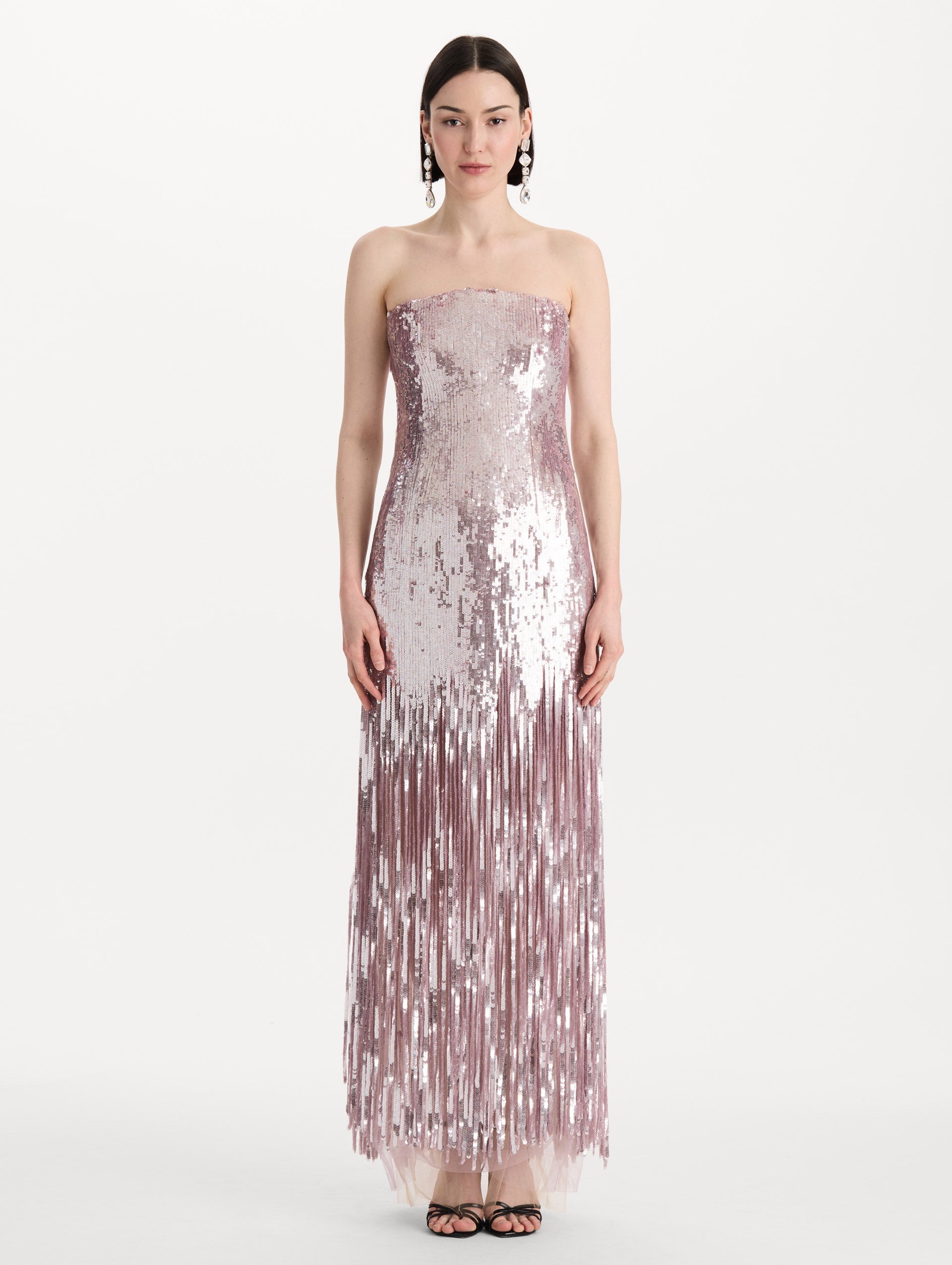 The model is wearing the Sequin Fringe Strapless Gown in the color tulip pink featuring a strapless silhouette, all-over sequins, and fringe skirt. Front View.