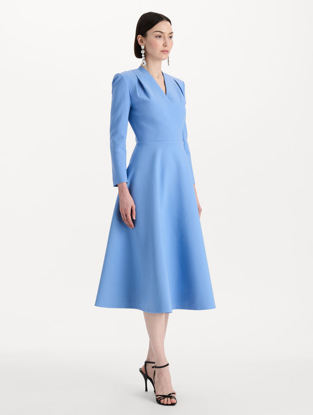 The model is wearing the Wool-Blend Long-Sleeve Dress in the color Hydrangea blue. Featuring a sculpted wrap bodice, long sleeves, and a flared skirt. Side View.