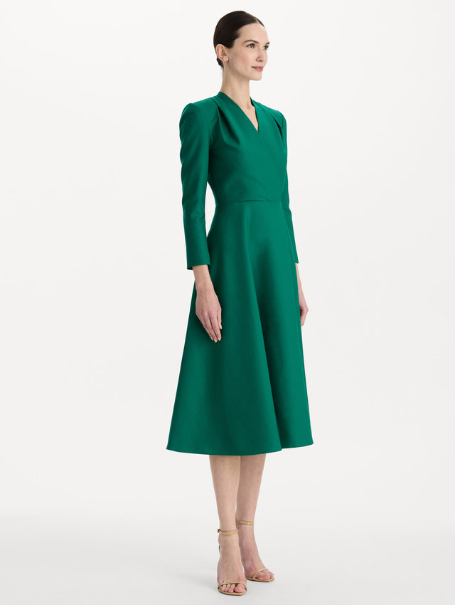 The model is wearing the Wool-Blend Long-Sleeve Dress in the color Malachite green. Featuring a sculpted wrap bodice, long sleeves, and a flared skirt. Side View.