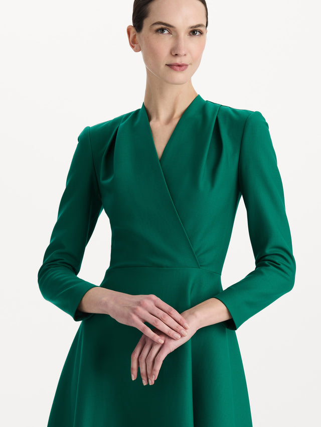 The model is wearing the Wool-Blend Long-Sleeve Dress in the color Malachite green. Featuring a sculpted wrap bodice, long sleeves, and a flared skirt. Detail Shot.