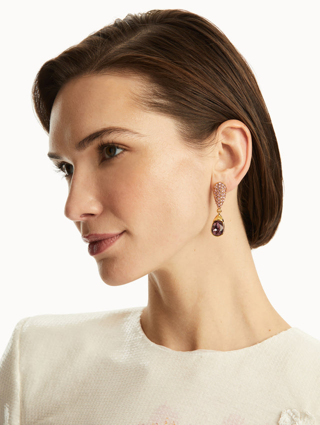 The model is wearing pave crystal drop earrings with an iris color crystal at the bottom. Front view.