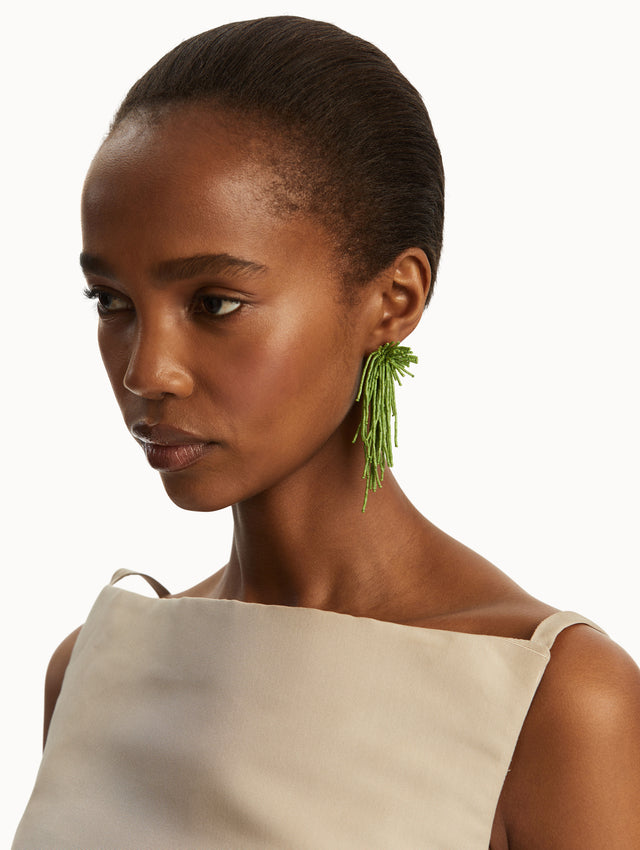 The model is wearing green beaded tassel earrings. Front view.