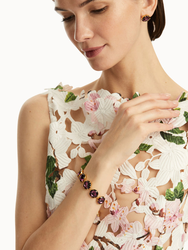 The model is wearing an iris color crystal bracelet, paired with a cherry blossom dress and matching earrings. Front view.