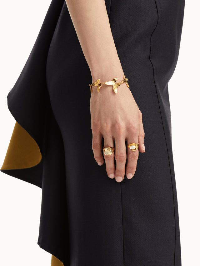 The model is wearing a gold lily pad ring with a pearl in the center, paired with another ring and bracelet. Front view.