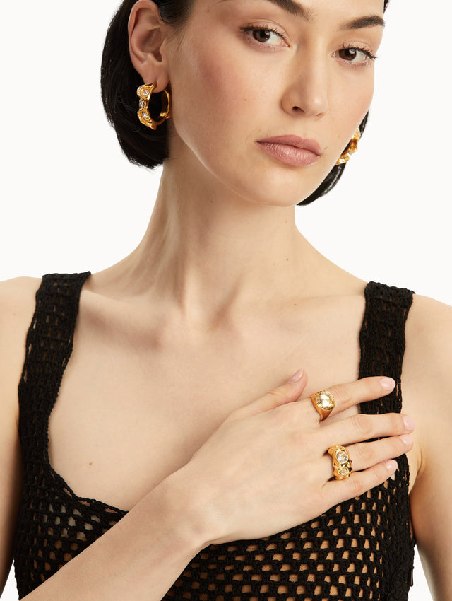 The model is wearing a gold textured ring with two crystals embedded. Front view.