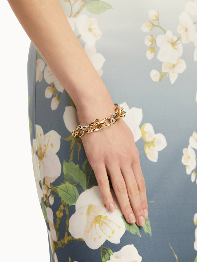 The model is wearing a bracelet with gold-tone links reminiscent of the Oscar 'O' emblem creating a knotted design. Front view