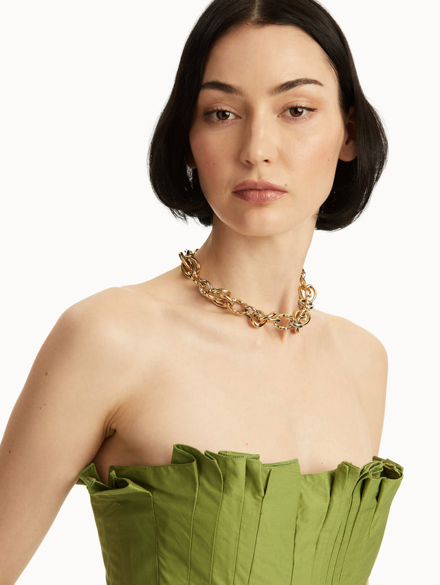 The model is wearing a necklace with gold-tone links reminiscent of the Oscar 'O' emblem creating a knotted design. Front view