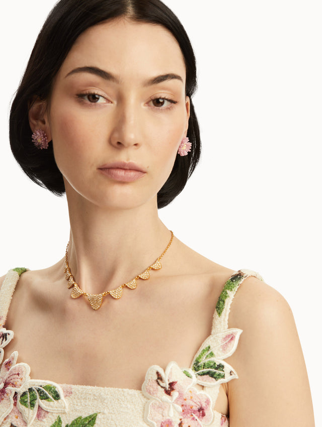 The model is wearing a gold chain-link necklace with pave scallops in the front. Front view