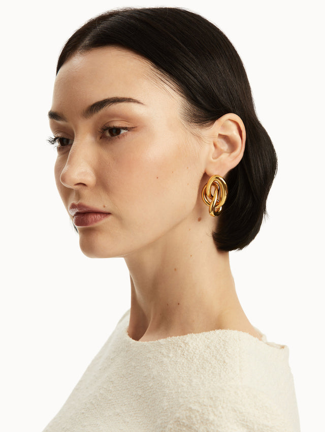 Model is wearing gold knot earrings, front view.