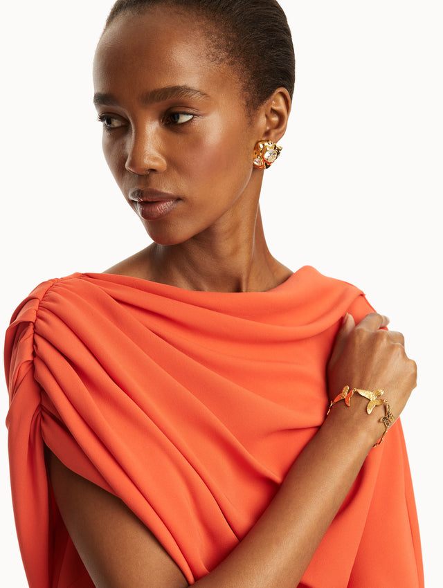 the model is wearing gold textured earrings embedded with two crystals and paired with a red gown. Front view