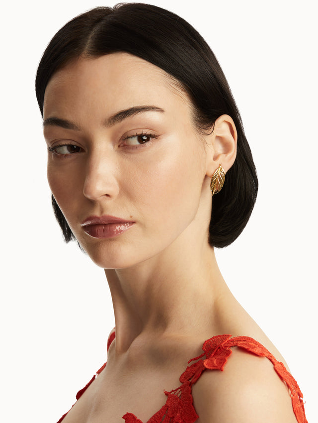 The model is wearing small gold leaf earrings. Front view
