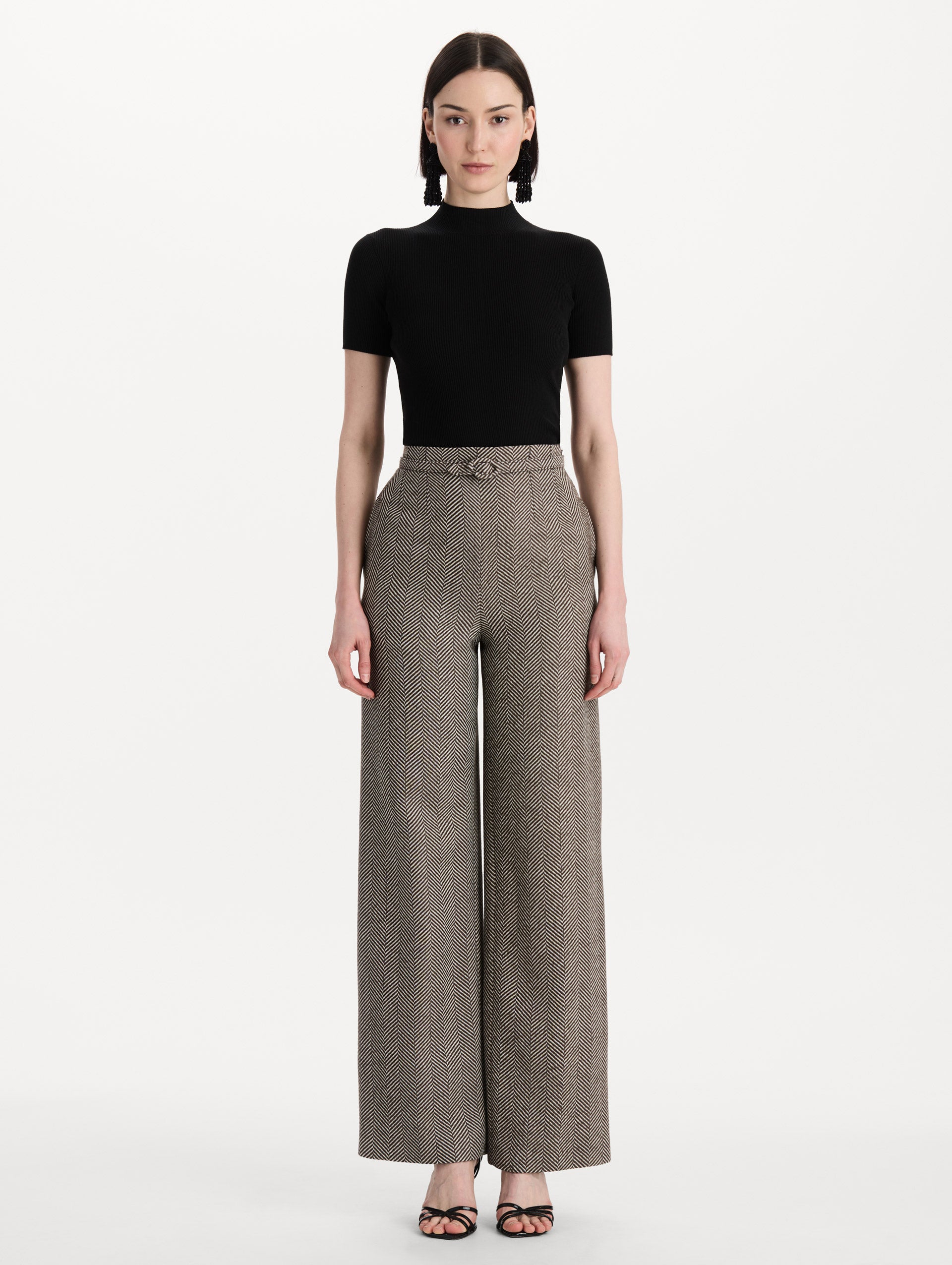 The model is wearing the Chevron Cashmere-Blend Pant featuring a high waist, pockets, and coordinating belt. Front View.