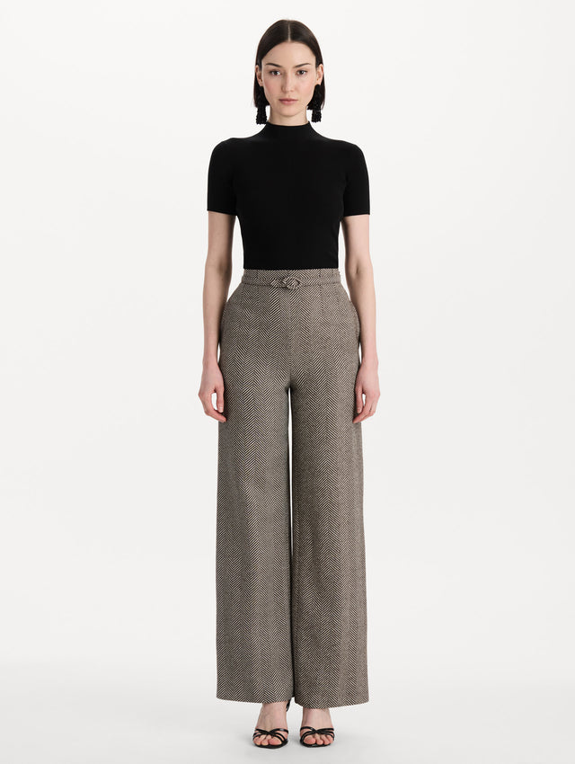 The model is wearing the Chevron Cashmere-Blend Pant featuring a high waist, pockets, and coordinating belt. Front View.