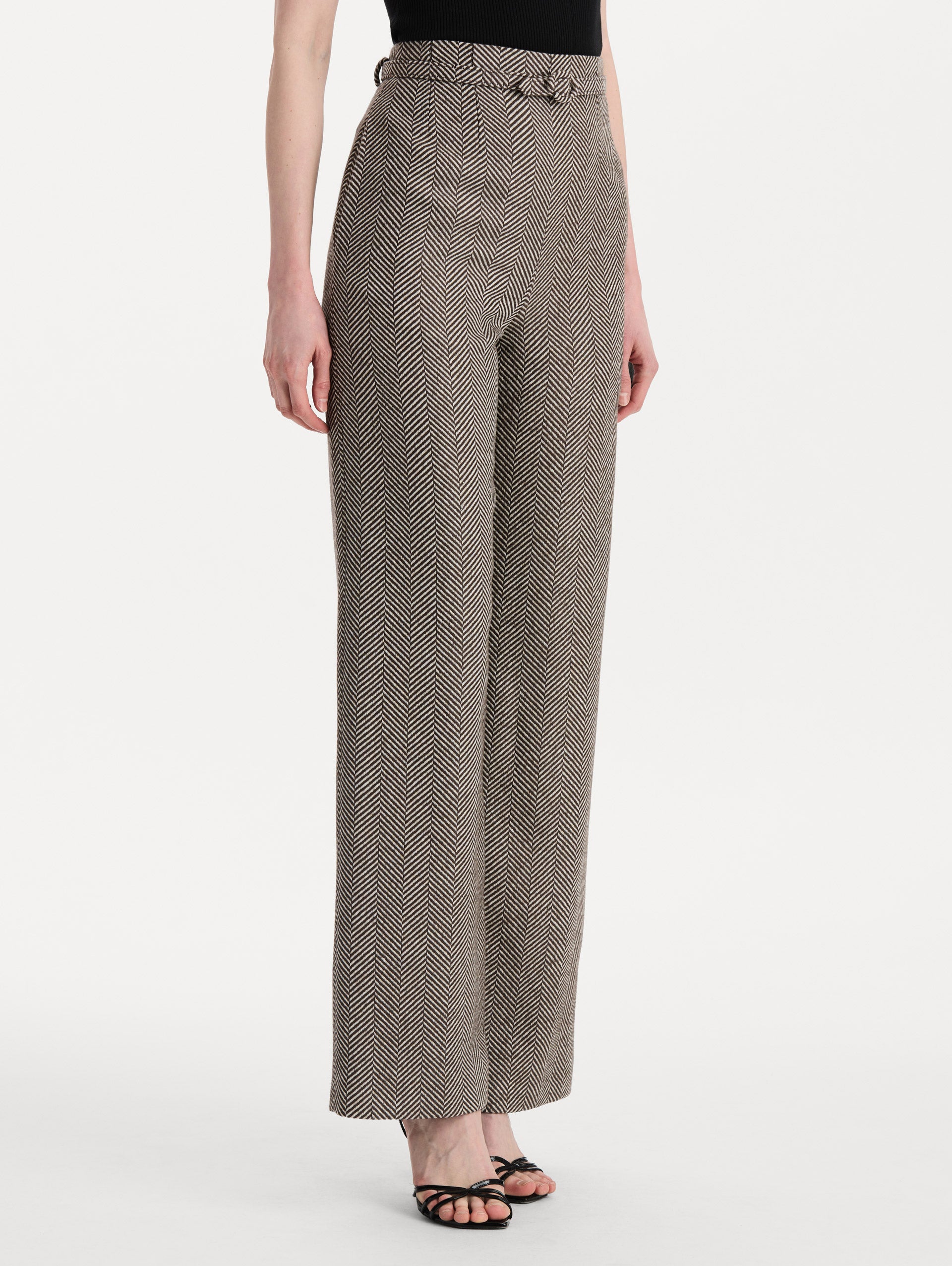 The model is wearing the Chevron Cashmere-Blend Pant featuring a high waist, pockets, and coordinating belt. Side View.