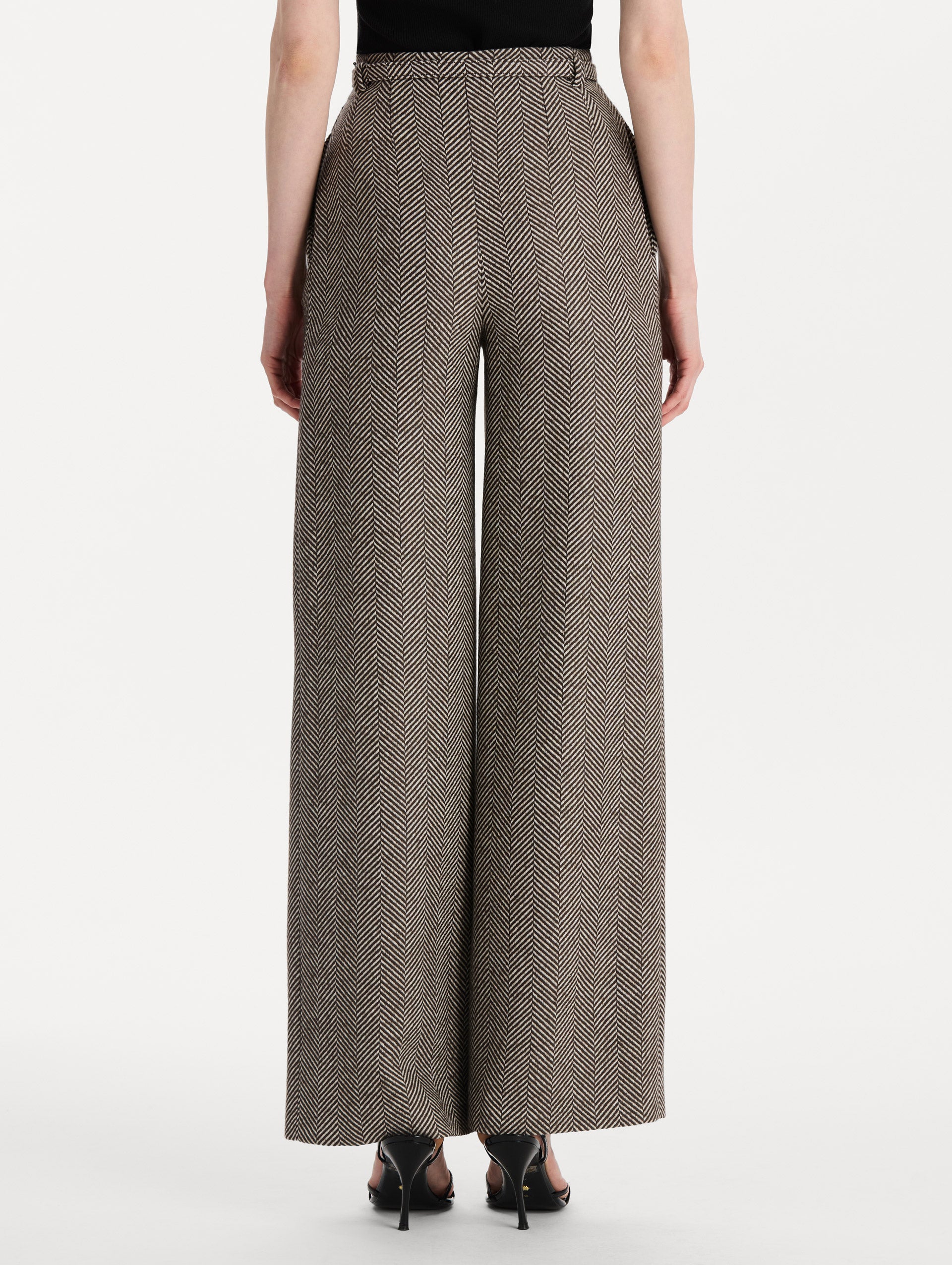 The model is wearing the Chevron Cashmere-Blend Pant featuring a high waist, pockets, and coordinating belt. Back View.