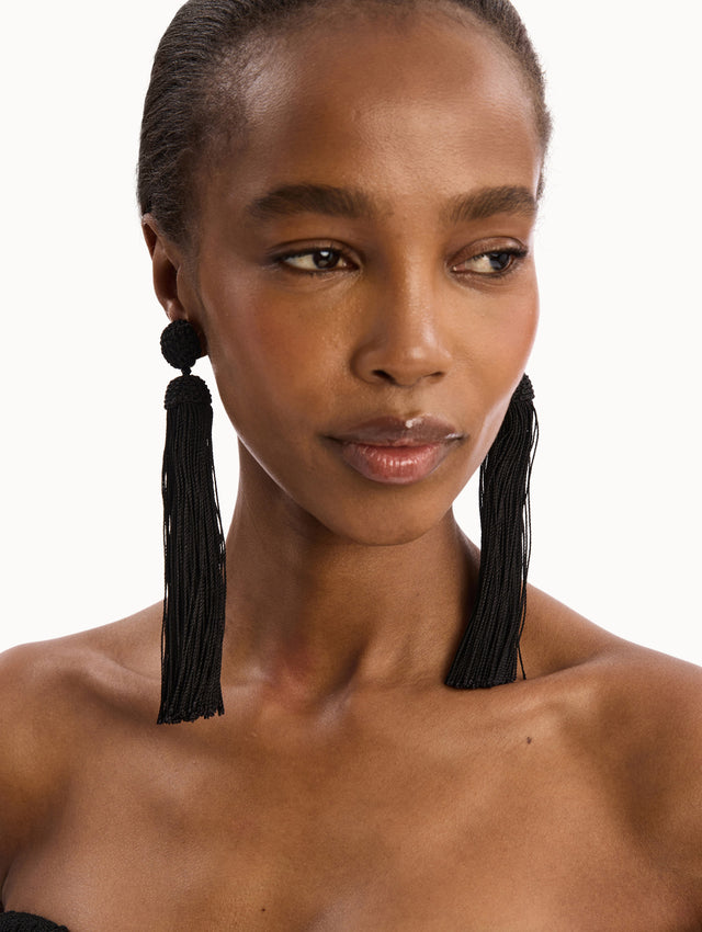 The model is wearing the Silk Rope Tassel Clip-On Earrings in Black. Detail View.