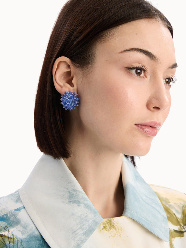 The model is wearing the Beaded Cluster Earrings in Sapphire Blue. Detail View.