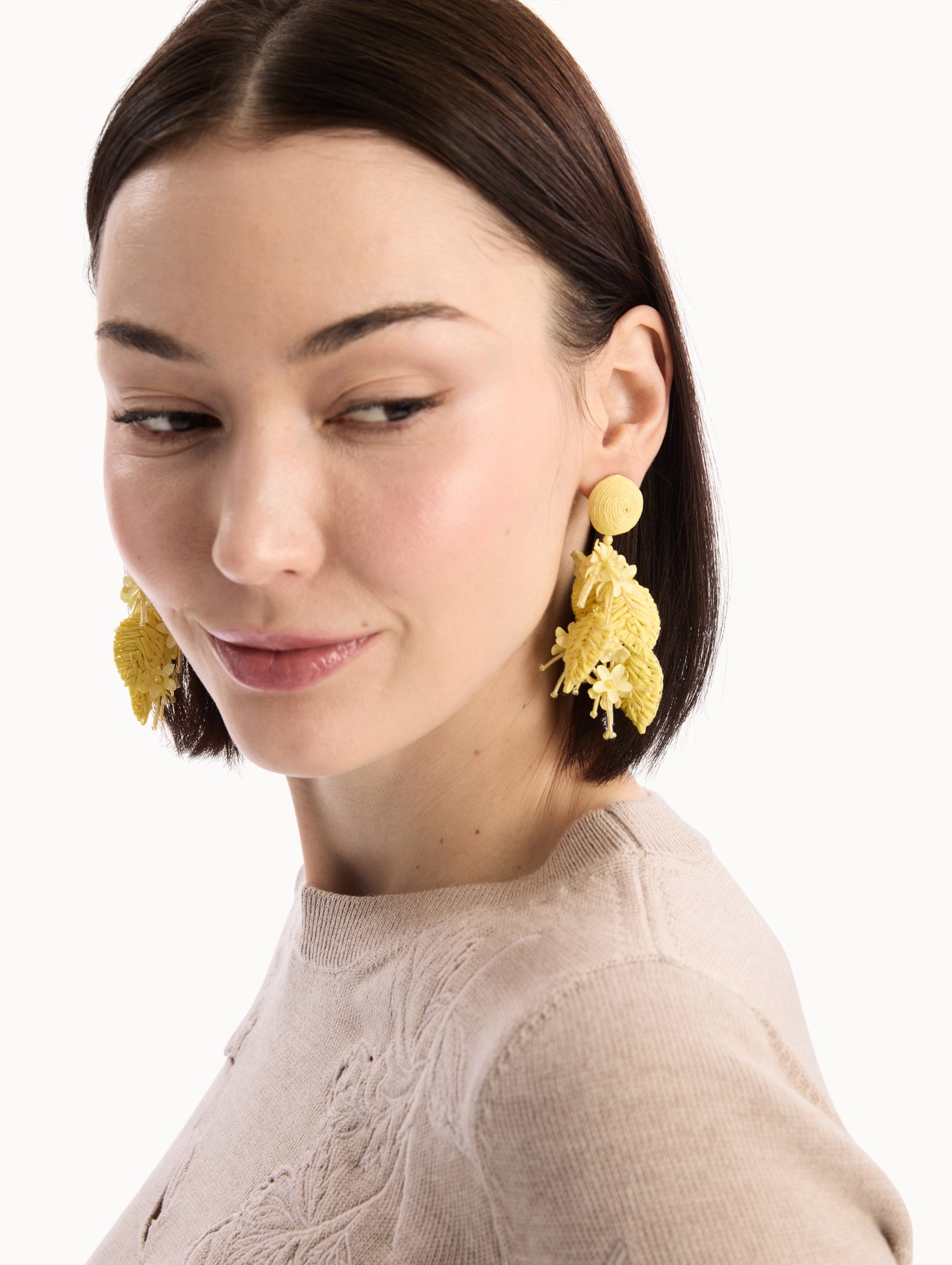 The model is wearing the Raffia Tassel Bouquet Clip-On Earrings in Yellow. Detail View.