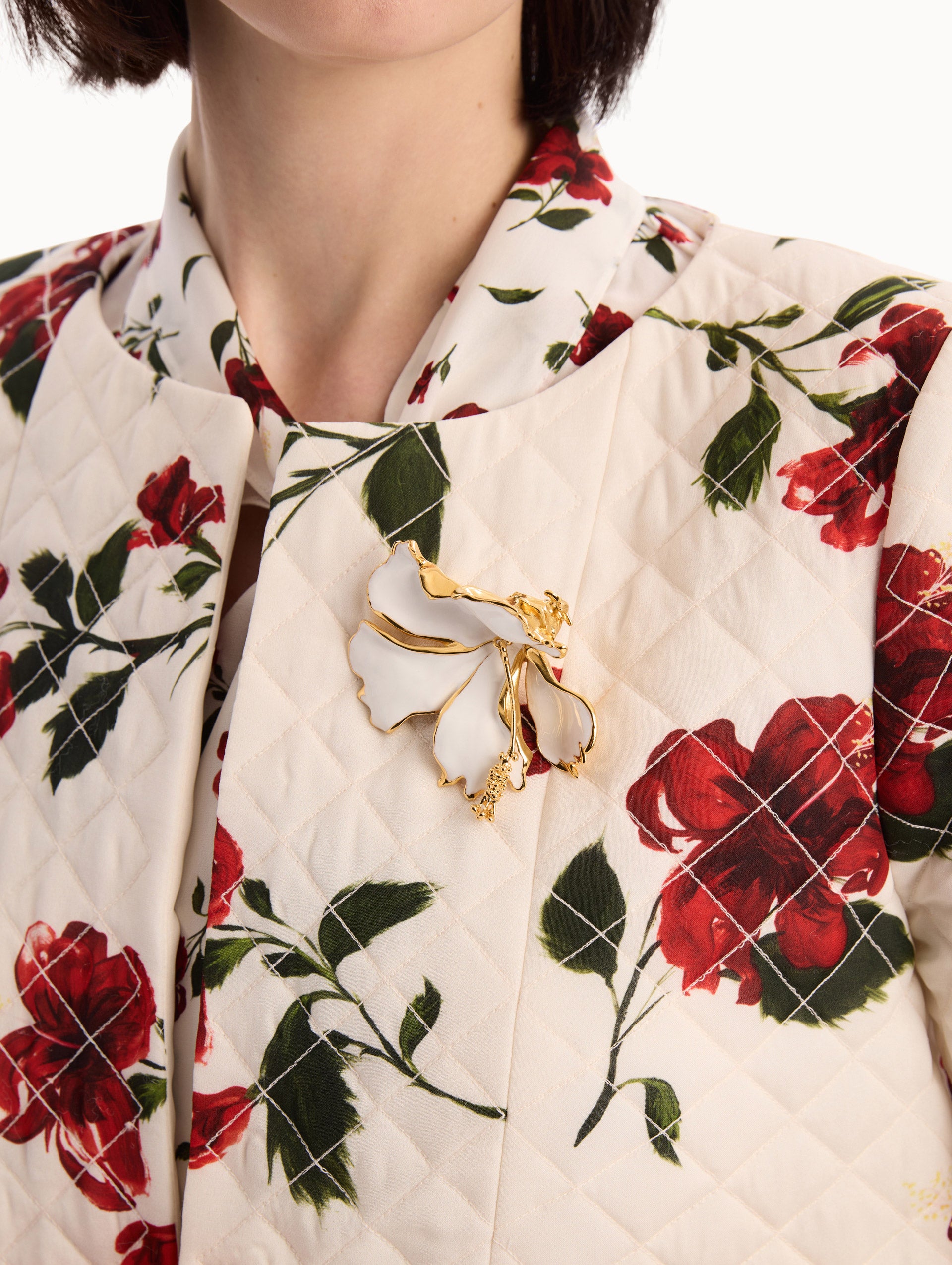 The model is wearing the Enamel Folded Hibiscus Brooch in White. Detail View.