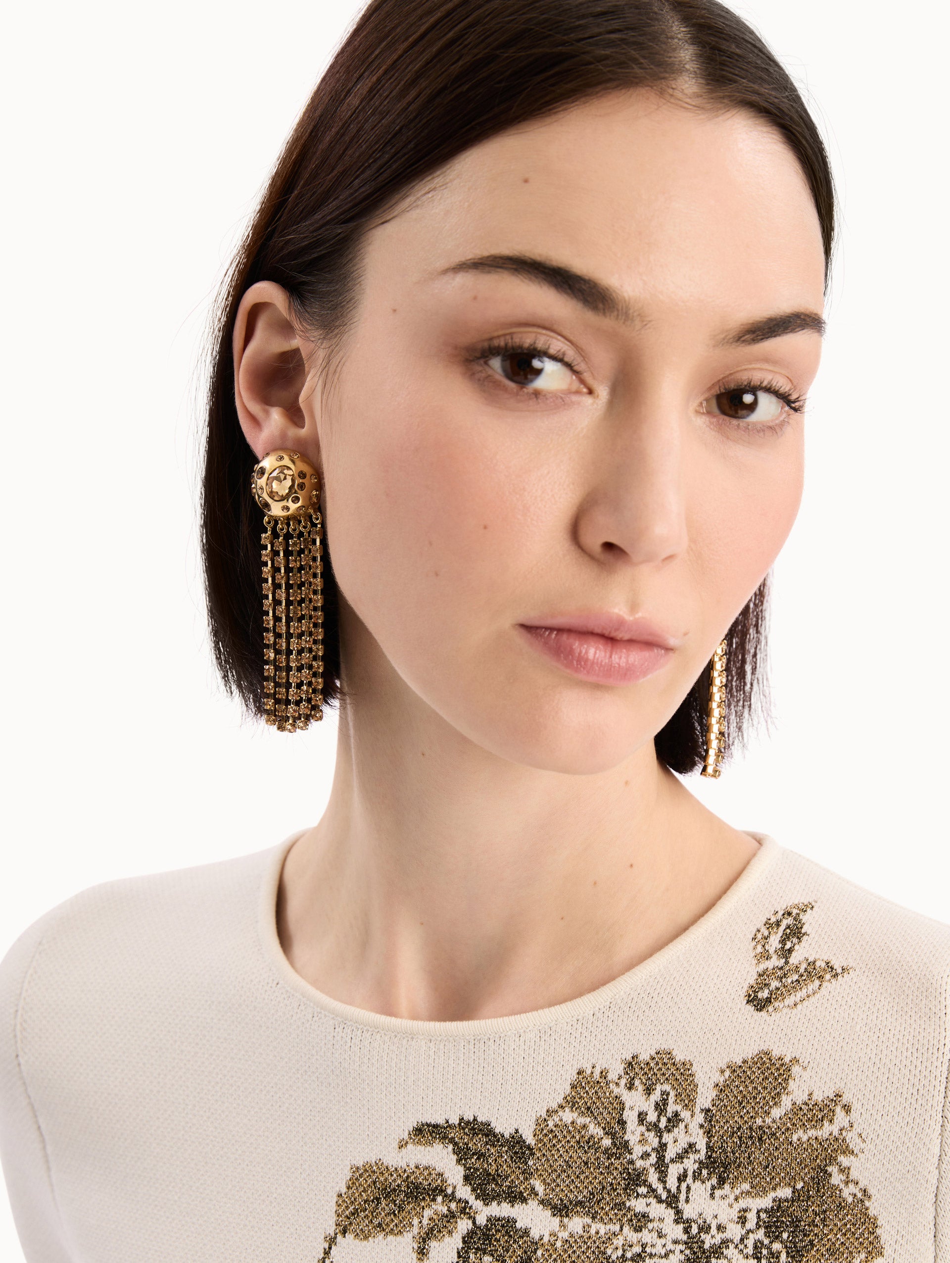 The model is wearing the Crystal Fringe Chandelier Earrings in Gold. Detail View.