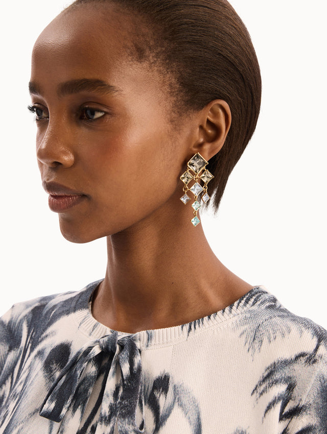 The model is wearing The Square-Cut Rhinestone Chandelier Clip-On Earrings in Sapphire Blue. Detail View.