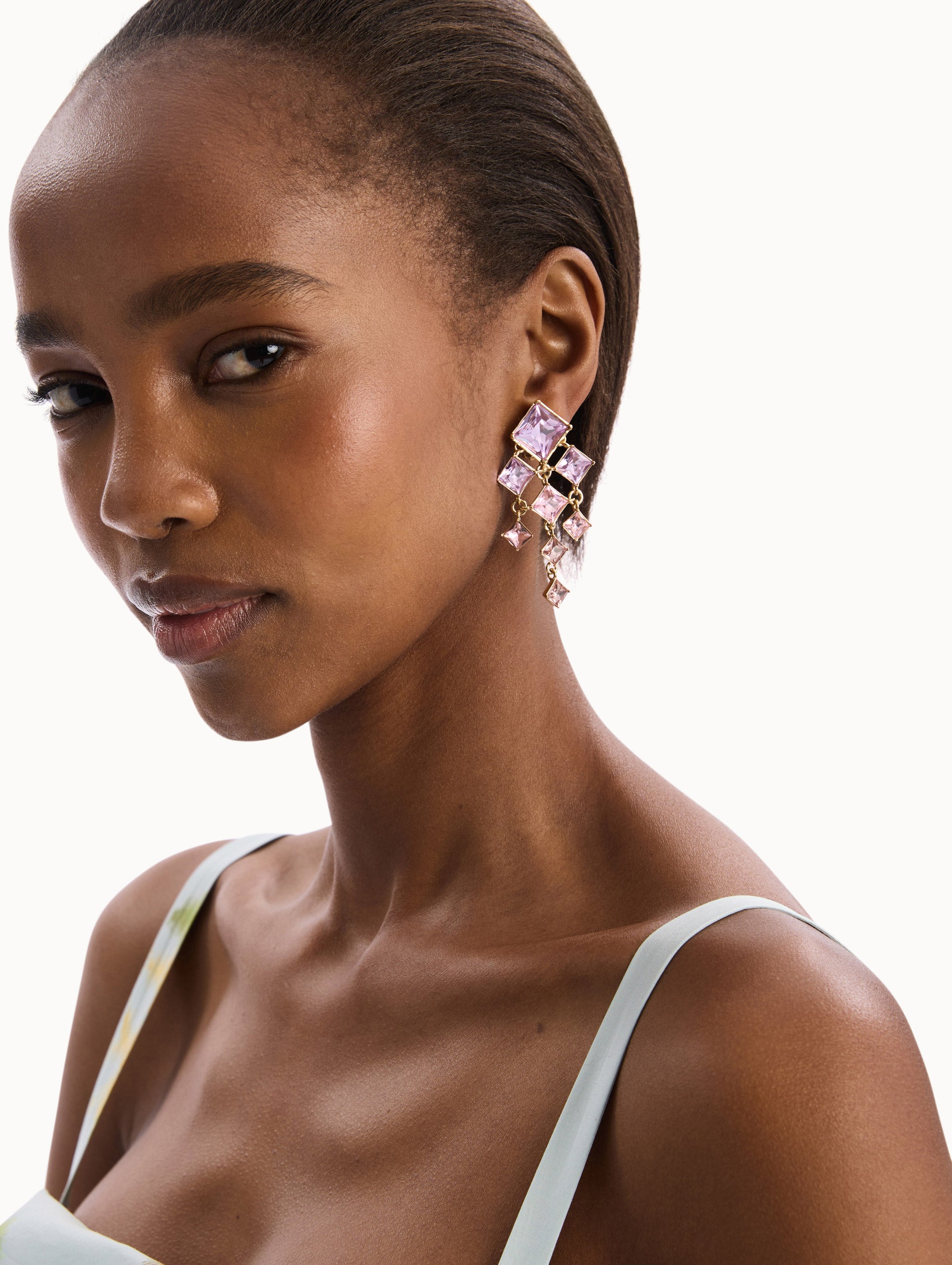 The model is wearing the Square-Cut Rhinestone Chandelier Clip-On Earrings in Violet. Detail View.