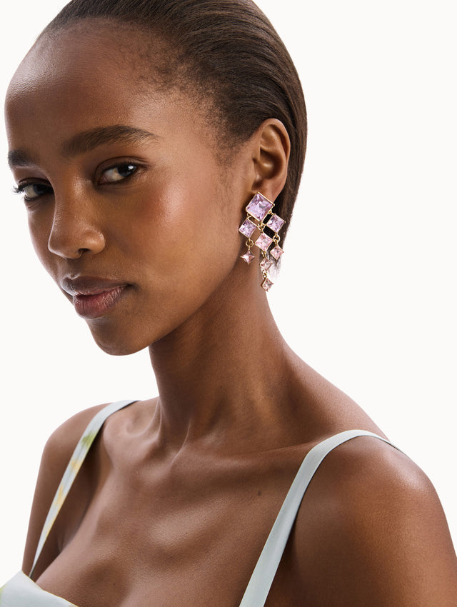 The model is wearing the Square-Cut Rhinestone Chandelier Clip-On Earrings in Violet. Detail View.