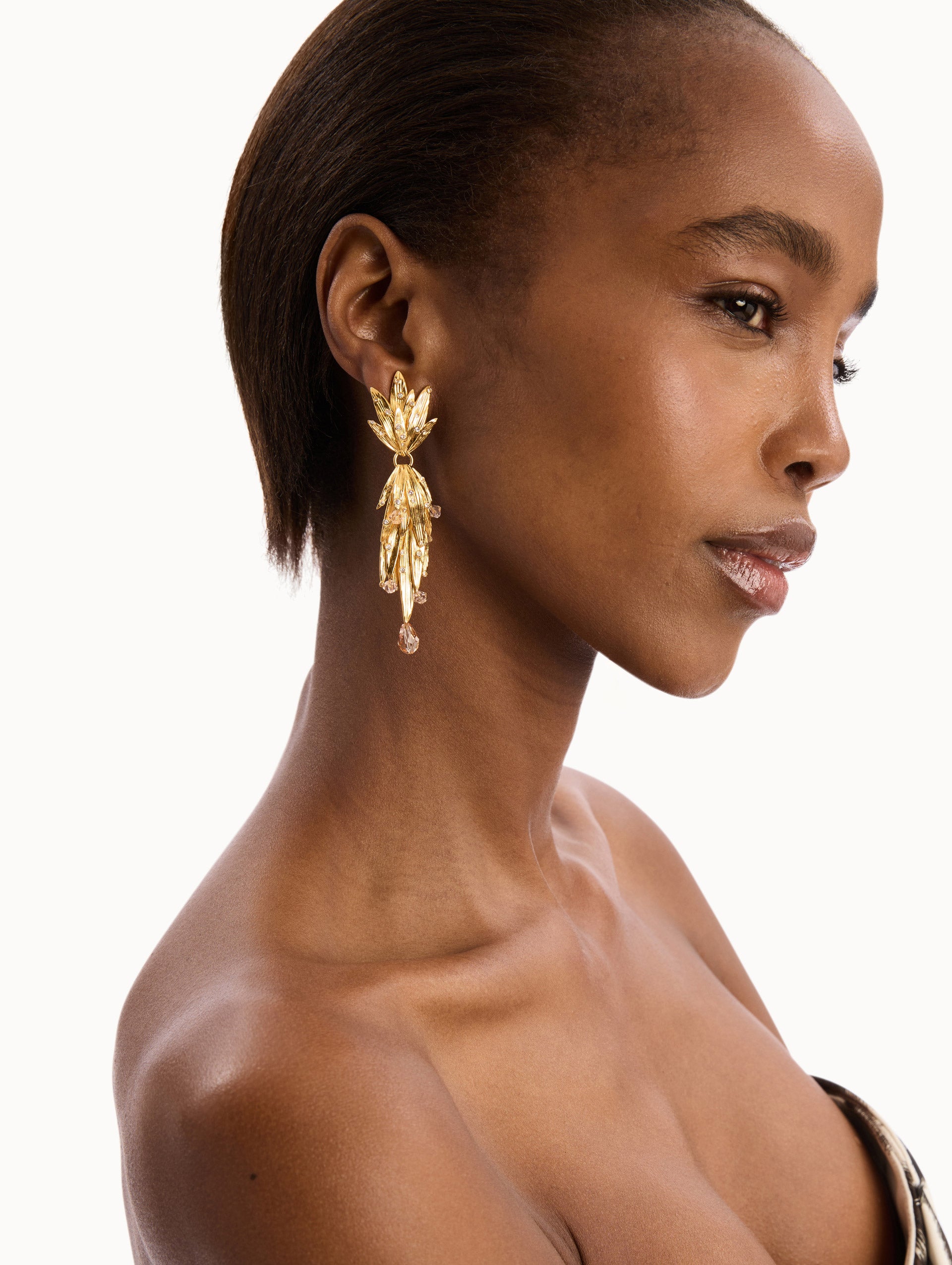 The model is wearing The Palm Leaf Clip-On Earrings in Gold with Crystal Accents. Detail View.
