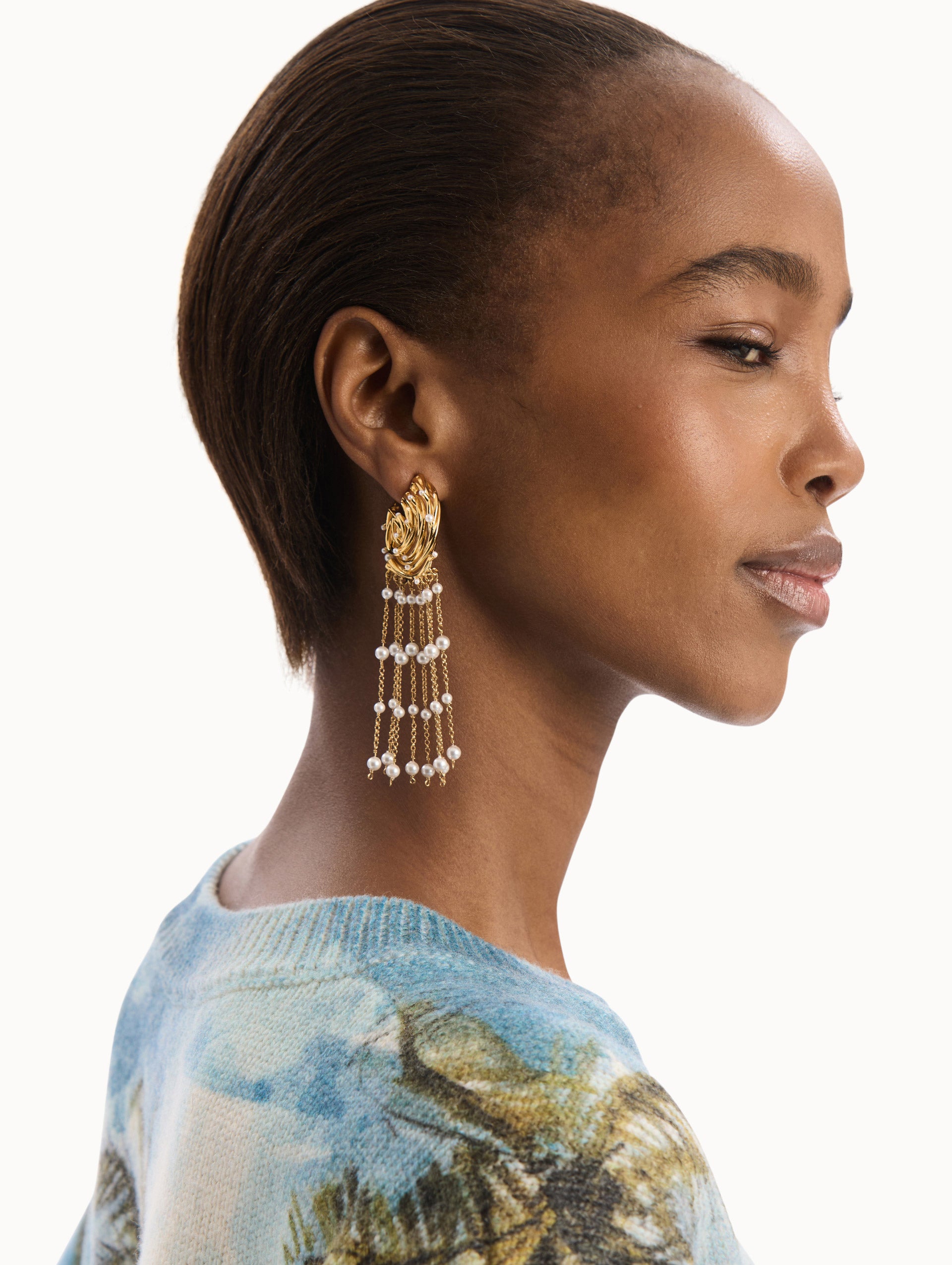The model is wearing the Pearl Nest Chandelier Clip-On Earrings in Gold. Detail View.