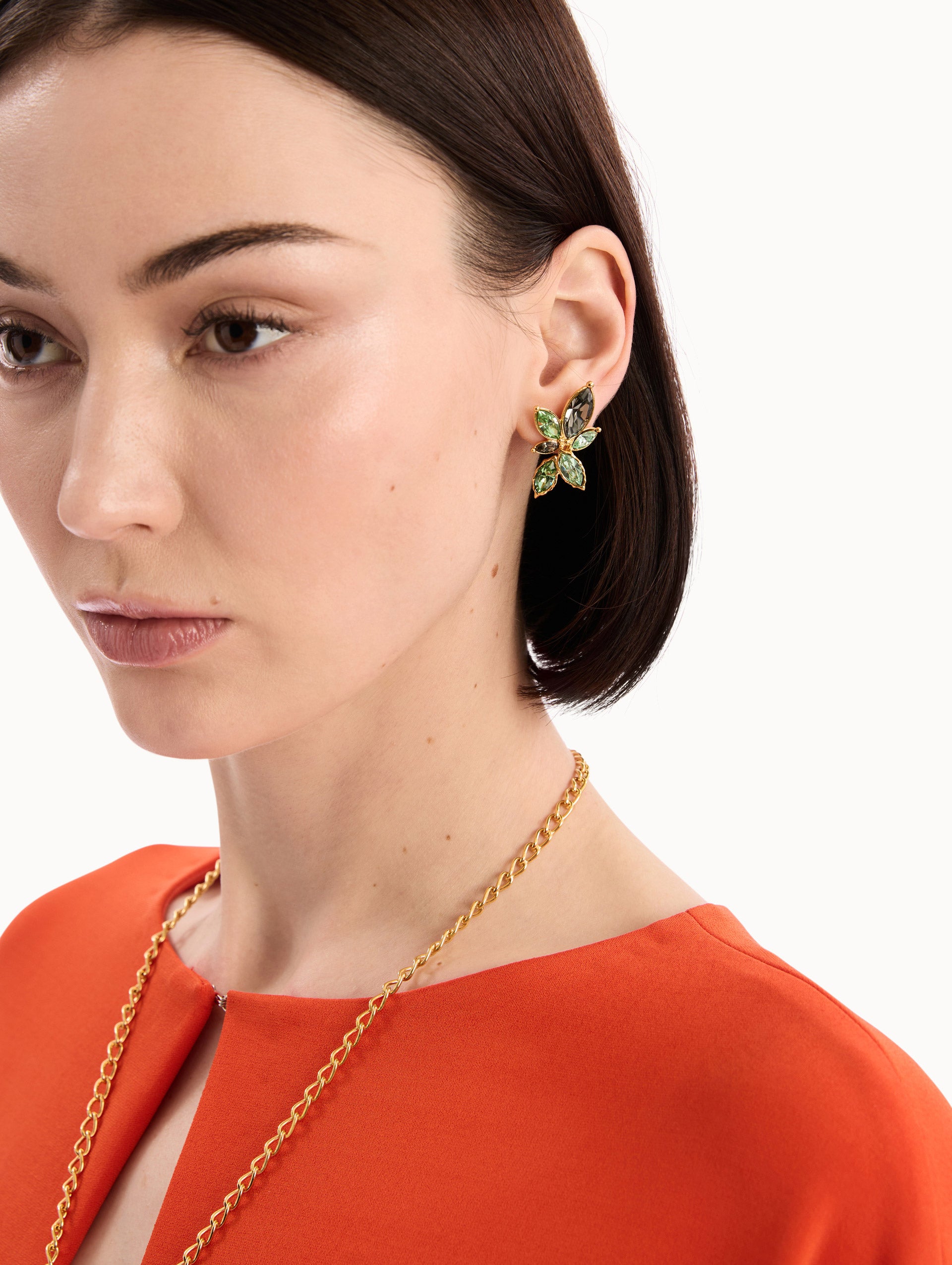 The model is wearing the Navette Crystal Clip-On Earrings in Peridot. Detail View.