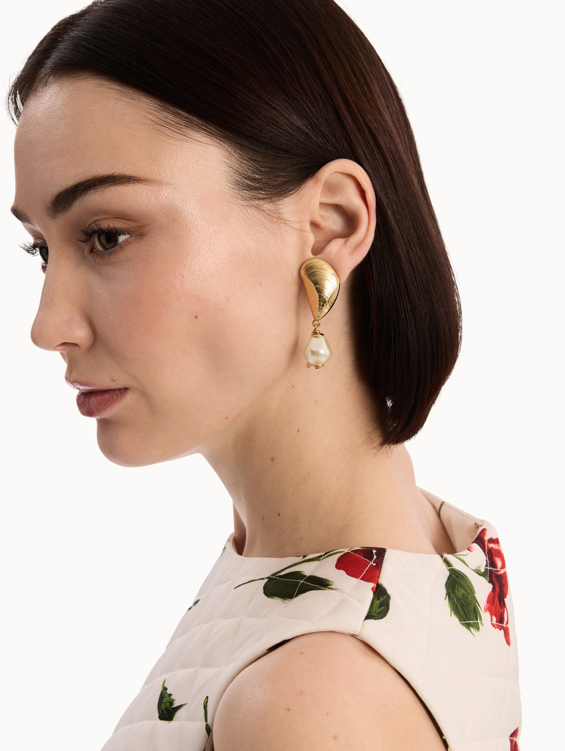 The model is wearing The Mussel Pearl Drop Clip-On Earrings in Gold with Pearl Accent. Detail View.
