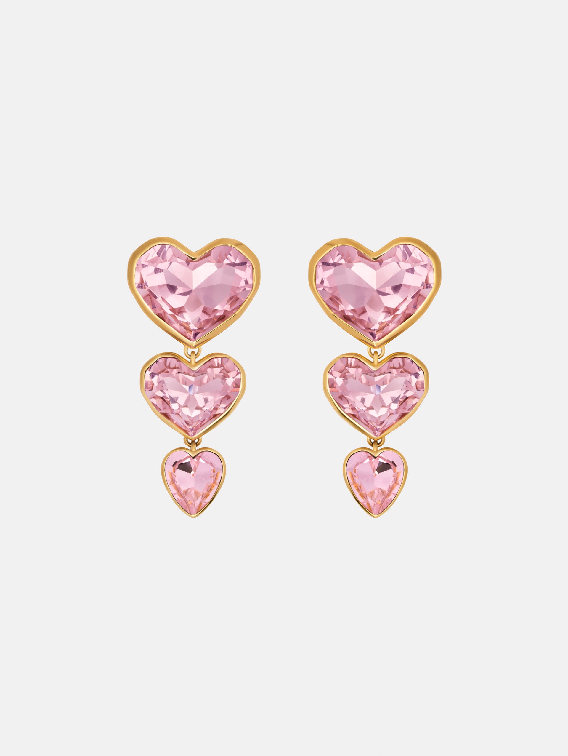 The Crystal Heart Drop Clip-On Earrings in Pink. Three vertically connected hearts with gold rims. Front View.