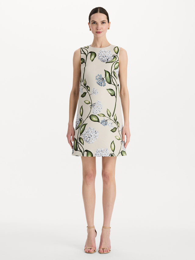 The model is wearing the Porcelain Flower Faille Shift Dress in white featuring a mini-length and printed floral motif. Front View.