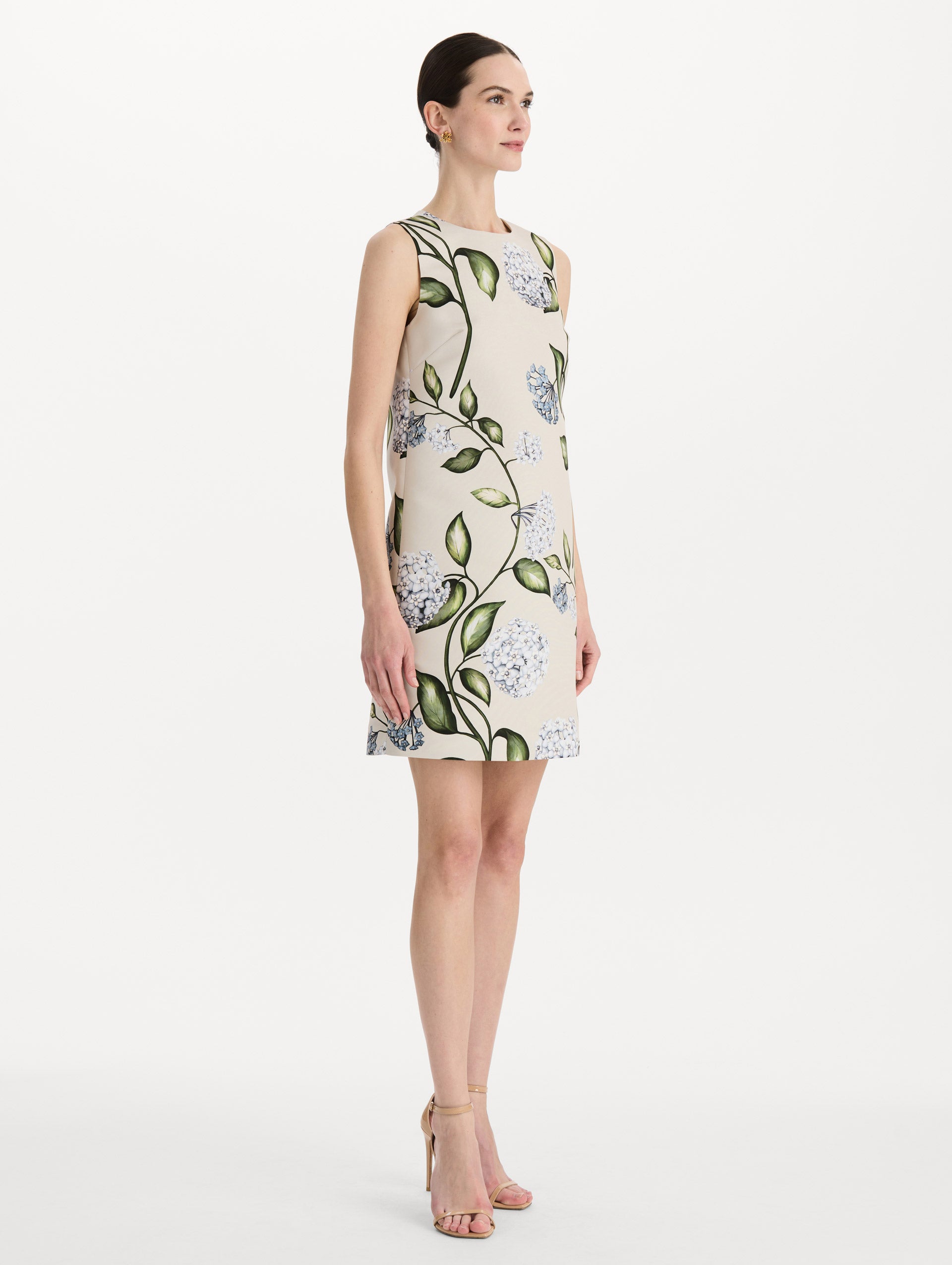 The model is wearing the Porcelain Flower Faille Shift Dress in white featuring a mini-length and printed floral motif. Side View.