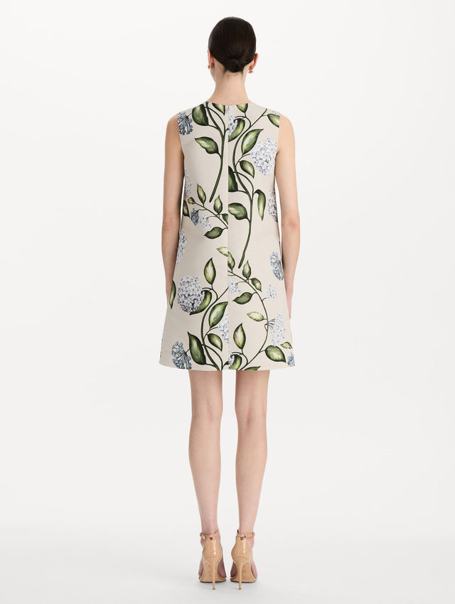 The model is wearing the Porcelain Flower Faille Shift Dress in white featuring a mini-length and printed floral motif. Back View.