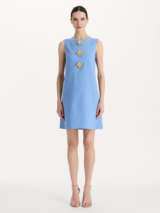The model is wearing the Button-Detail Wool Shift Dress in the color Hydrangea blue in a mini-length, featuring bold, floral gold buttons. Front View.