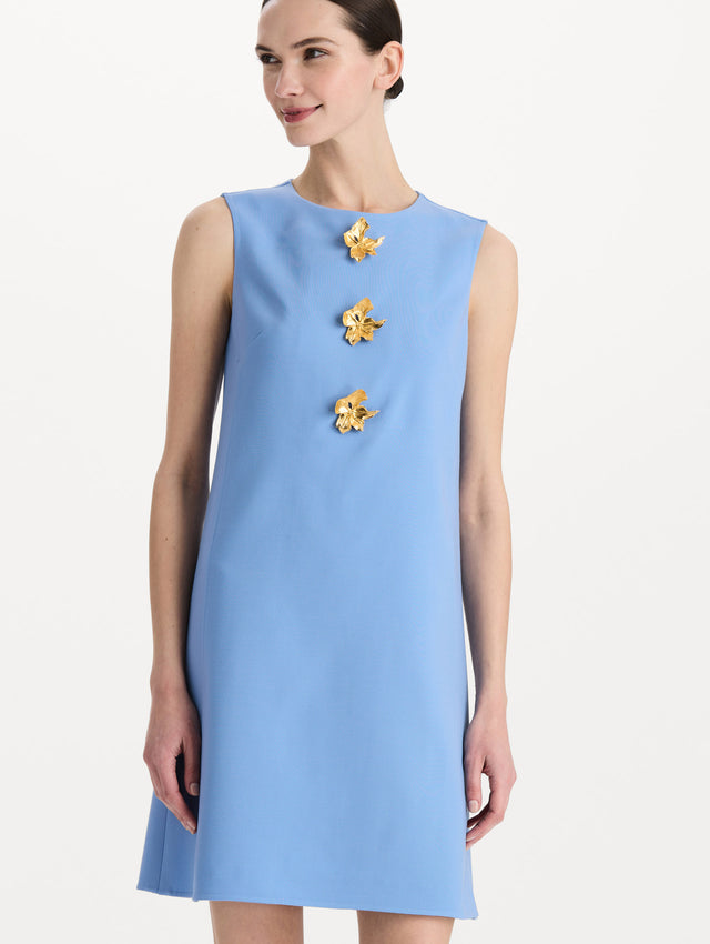 The model is wearing the Button-Detail Wool Shift Dress in the color Hydrangea blue in a mini-length, featuring bold, floral gold buttons. Detail Shot.