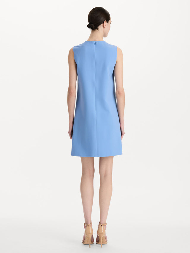 The model is wearing the Button-Detail Wool Shift Dress in the color Hydrangea blue in a mini-length, featuring bold, floral gold buttons. Back View.
