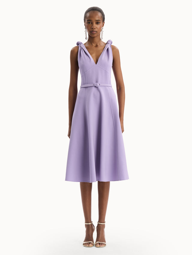 The model is wearing the Twist-Detailed Wool Dress in Purple featuring a deep V-neckline and belt at waist. Front View.