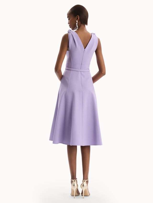The model is wearing the Twist-Detailed Wool Dress in Purple featuring a deep V-neckline and belt at waist. Back View.