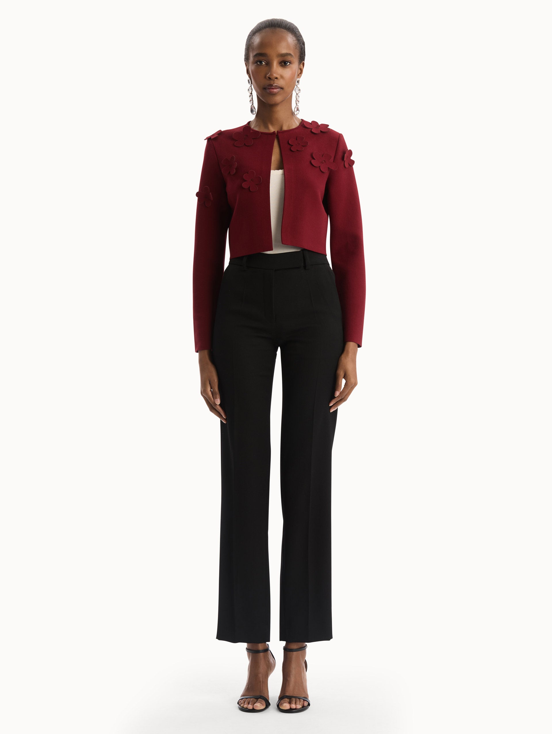 The model is wearing the Laser-Cut Floral Knit Cardigan in a wine, red color with sculptural floral appliqués. Front View.