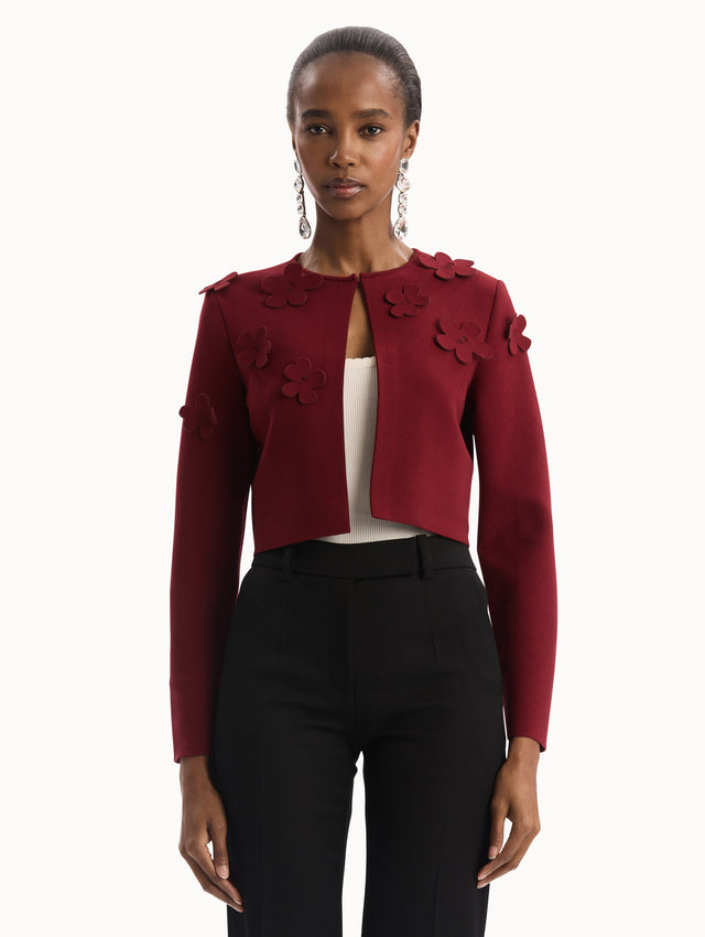 The model is wearing the Laser-Cut Floral Knit Cardigan in a wine, red color with sculptural floral appliqués. Front View.