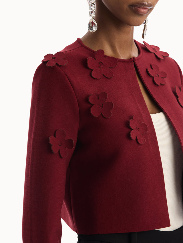 The model is wearing the Laser-Cut Floral Knit Cardigan in a wine, red color with sculptural floral appliqués. Side View.
