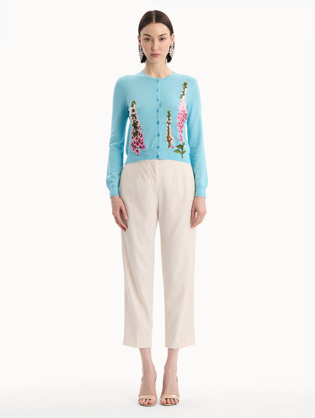 The model is wearing the Foxglove Threadwork Cardigan in vibrant light blue color with floral embroidery and buttons along the center. Front View.