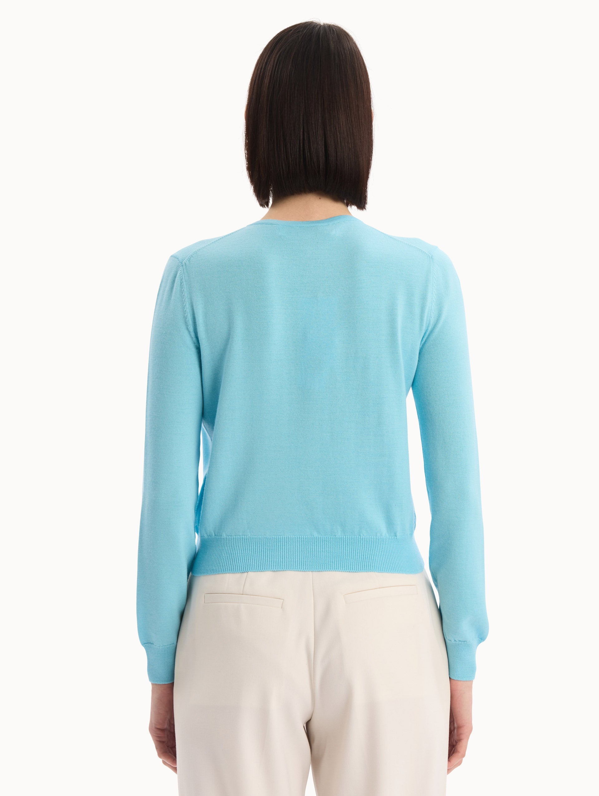 The model is wearing the Foxglove Threadwork Cardigan in vibrant light blue color with floral embroidery and buttons along the center. Back View.