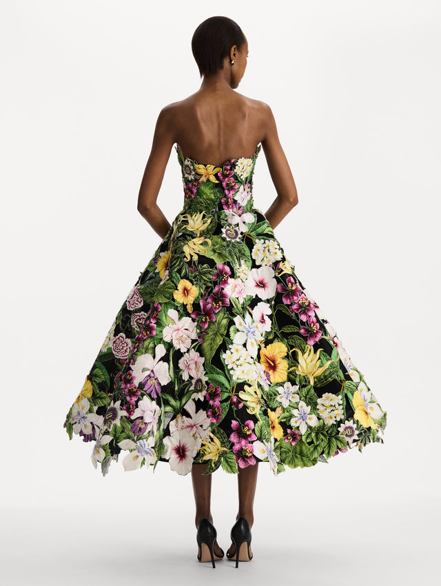 The model is wearing the Dominican Mixed-Floral Guipure Gown. Featuring a strapless neckline, fitted bodice, and full skirt. Back View.