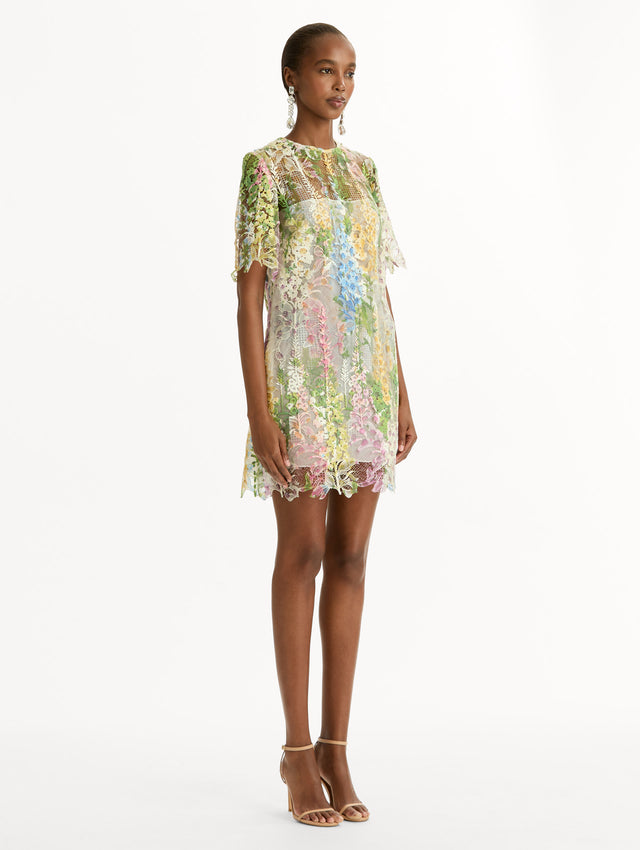 White and floral Foxglove Guipure Shift Dress with multi color sheer floral overlay and a white lining underneath. Side View.