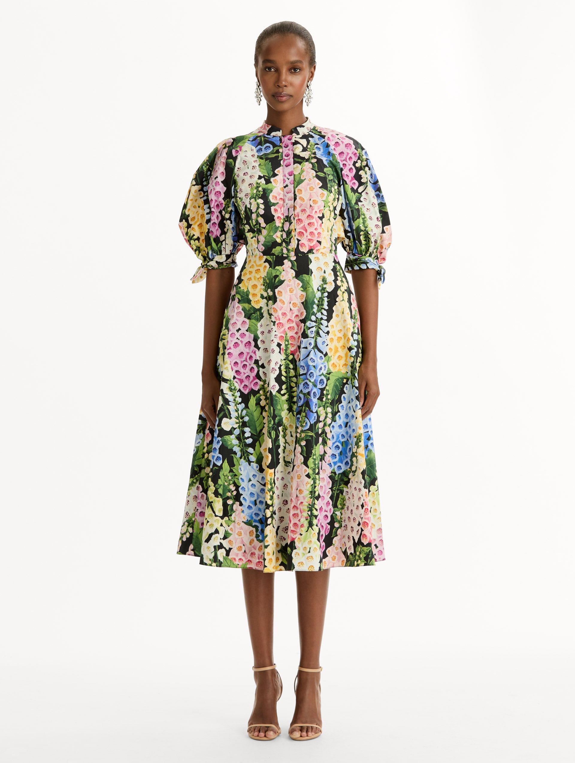 Black floral Foxglove Cotton Poplin Puff Sleeve Dress with voluminous elbow-length puff sleeves, a fitted waist, and a flared skirt that falls below the knee. Front View.
