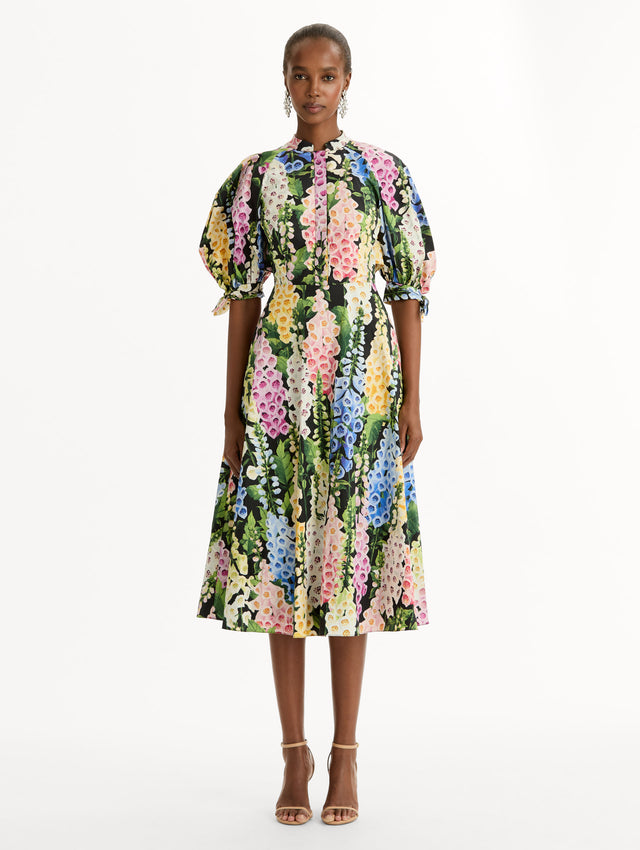 Black floral Foxglove Cotton Poplin Puff Sleeve Dress with voluminous elbow-length puff sleeves, a fitted waist, and a flared skirt that falls below the knee. Front View.